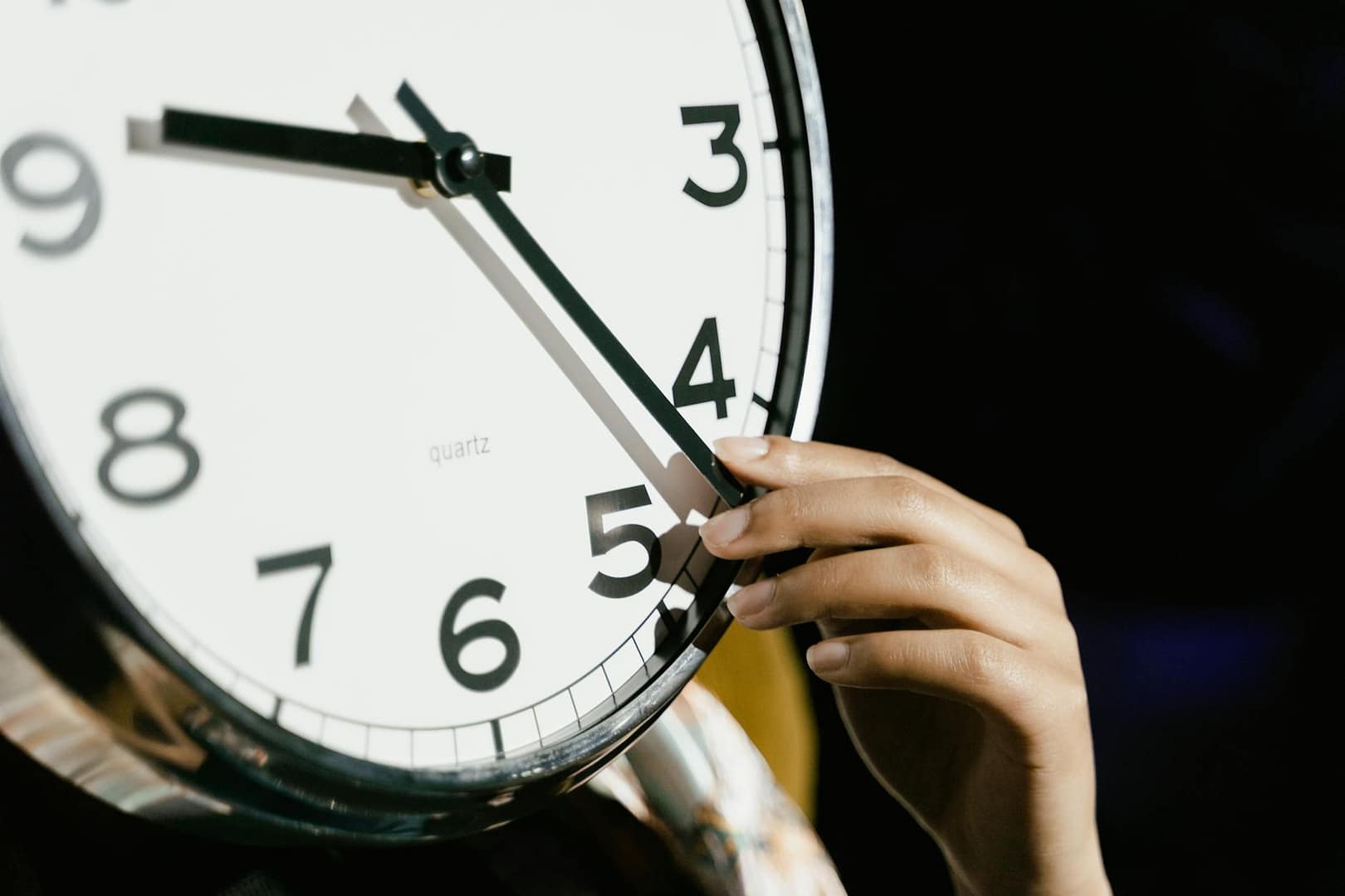 person holding white analog clock
